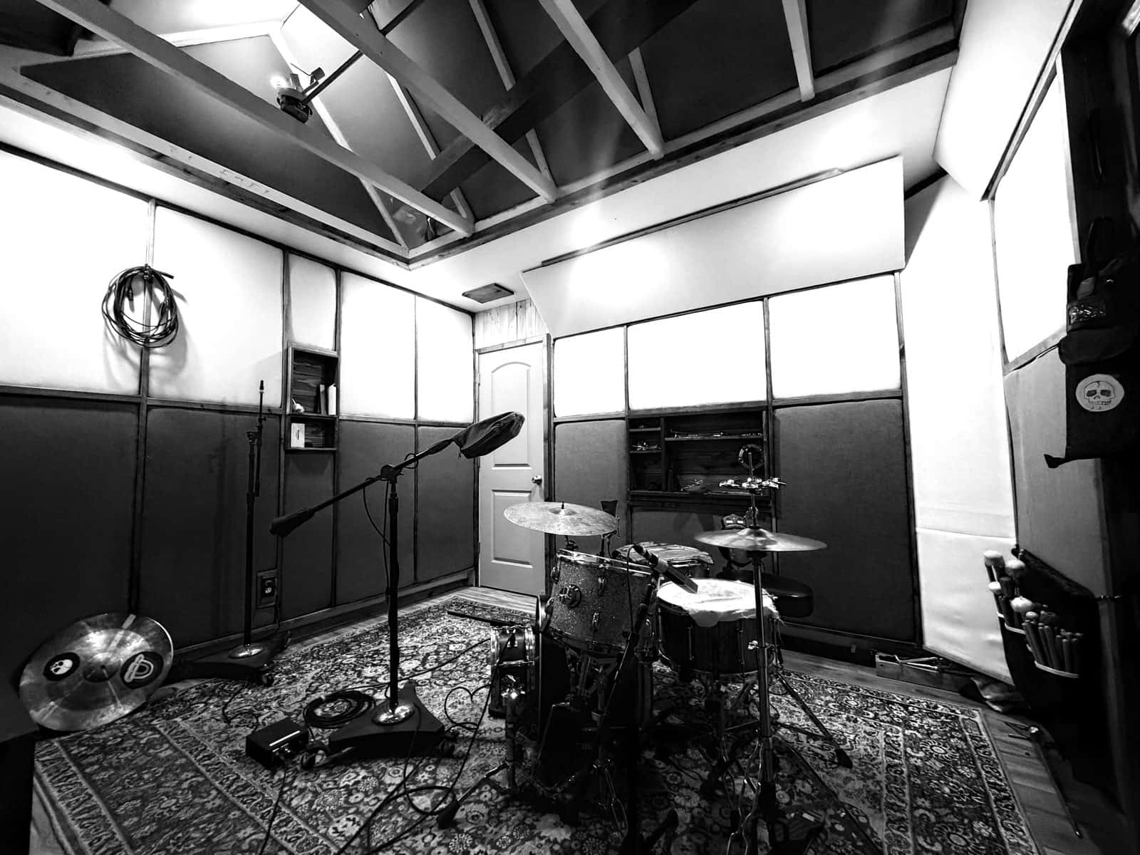The live room: a sparkle-finish drum kit and boom microphone set up on a Persian rug beneath a vaulted, acoustically treated ceiling.