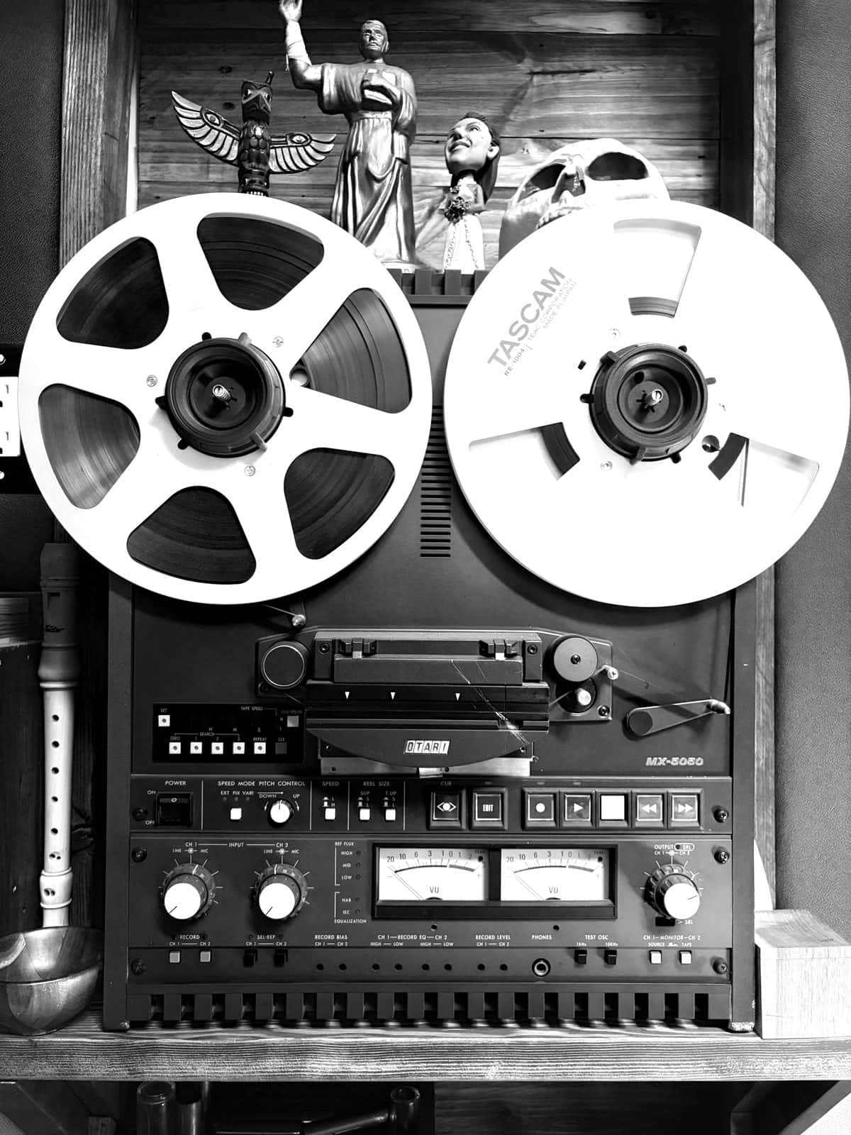 Otari MX-5050 reel-to-reel tape machine with Tascam reels, skull and figurines on the shelf above.